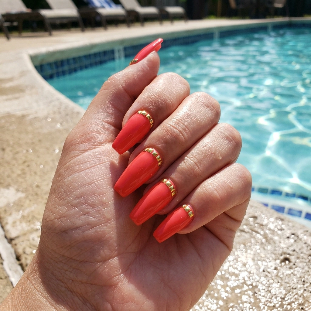Coral red nails with gold studs.