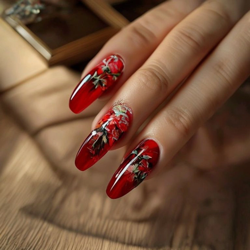 Close-up of a hand with a floral red manicure applying cuticle oil to the nails. Neat wooden vanity, soft ambient lighting.