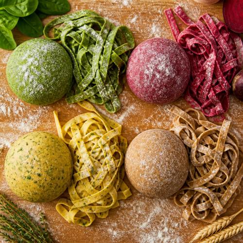 Colorful pasta dough variations featuring spinach green, beetroot red, and herb-laminated sheets
