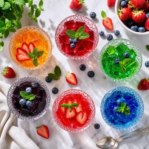 Overhead flat lay of colorful low-calorie sugar-free jello treats in crystal dessert glasses garnished with fresh berries